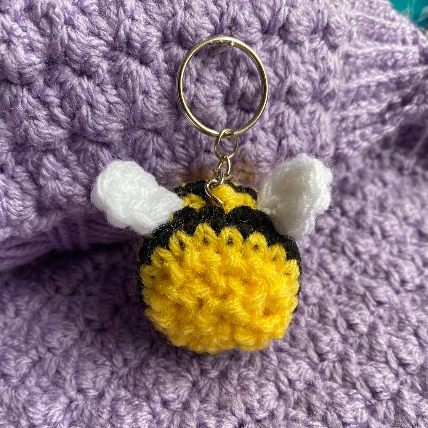 Cute crochet bee keyring with a purple yarn background