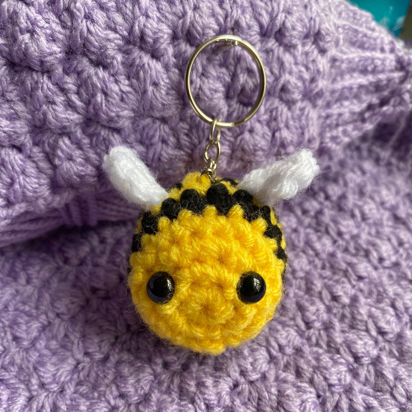 Cute crochet bee keyring with a purple yarn background