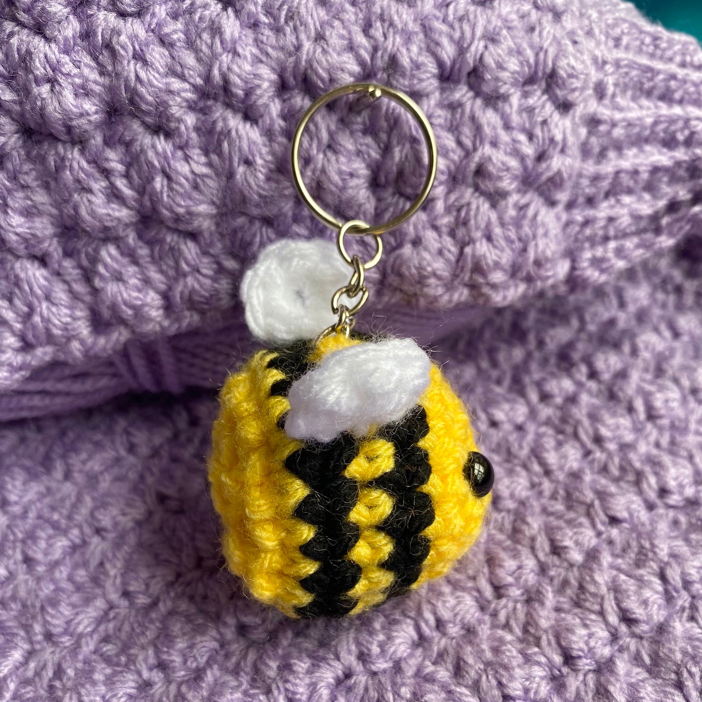 Cute crochet bee keyring with a purple yarn background