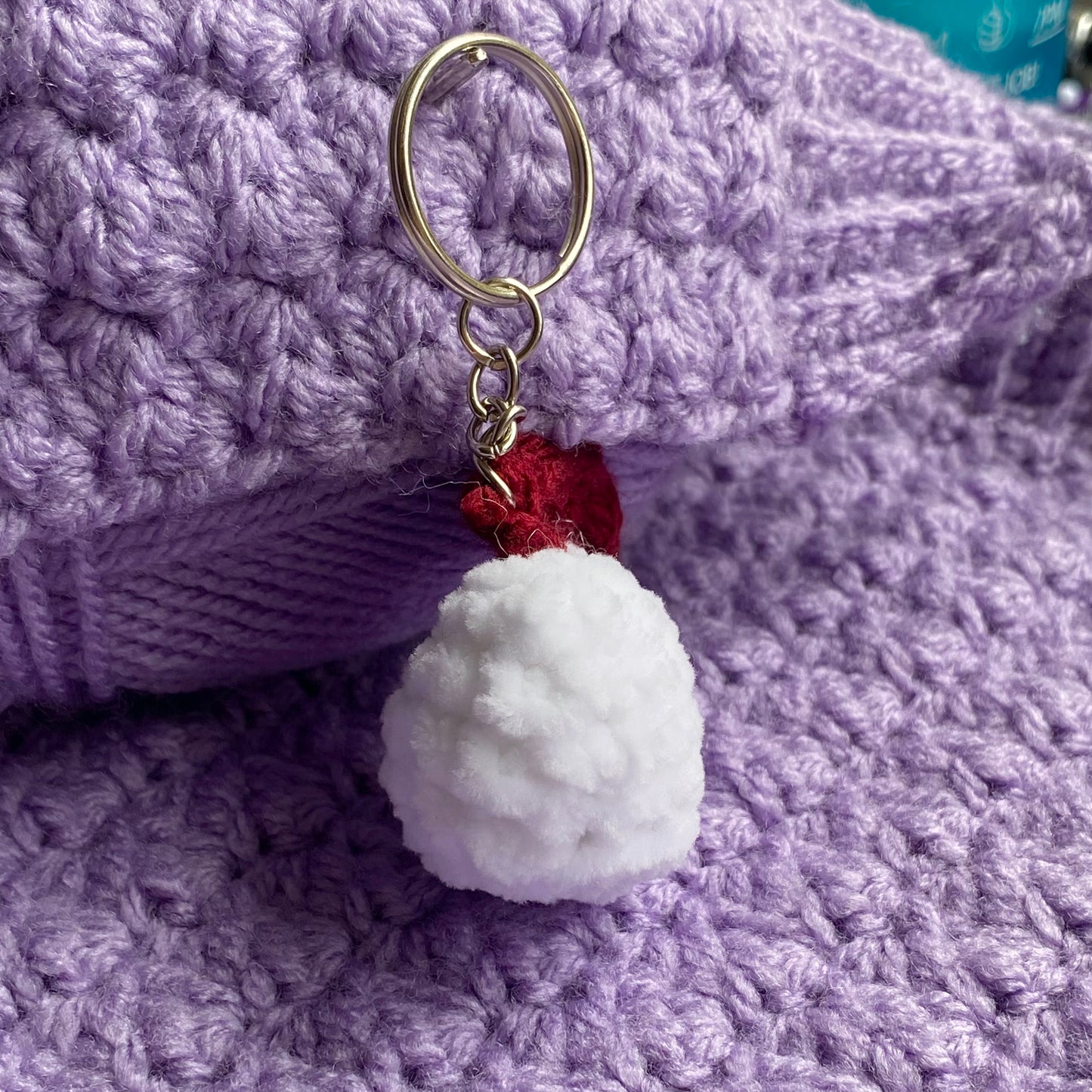 Crochet cute chicken keyring on a purple yarn background