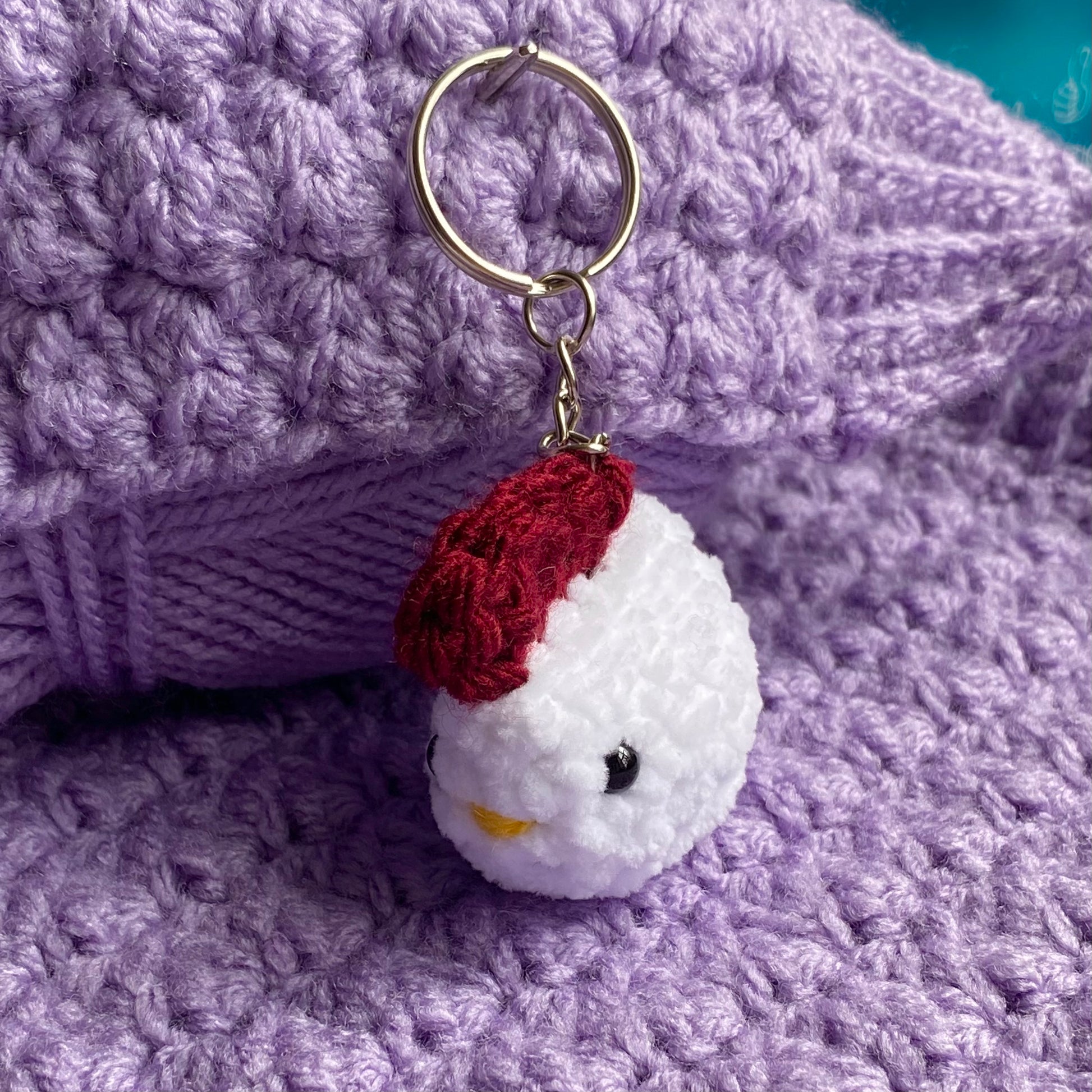 Crochet cute chicken keyring on a purple yarn background
